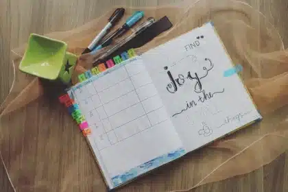 Mains tenant un calendrier ou un carnet de suivi des cycles menstruels avec des éléments de bien-être