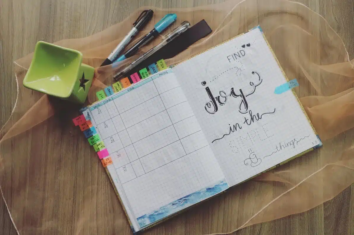 Mains tenant un calendrier ou un carnet de suivi des cycles menstruels avec des éléments de bien-être