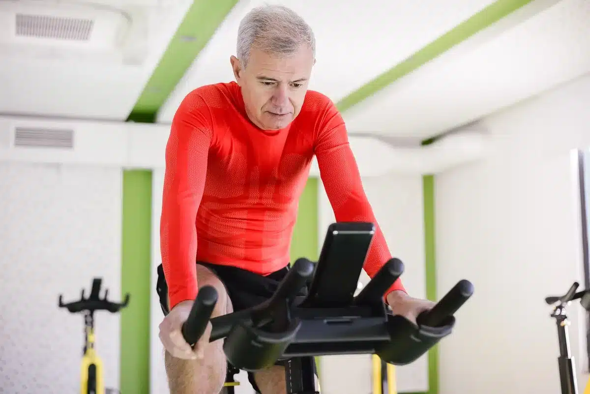 Personne âgée pratiquant le vélo stationnaire, exercice à faible impact.
