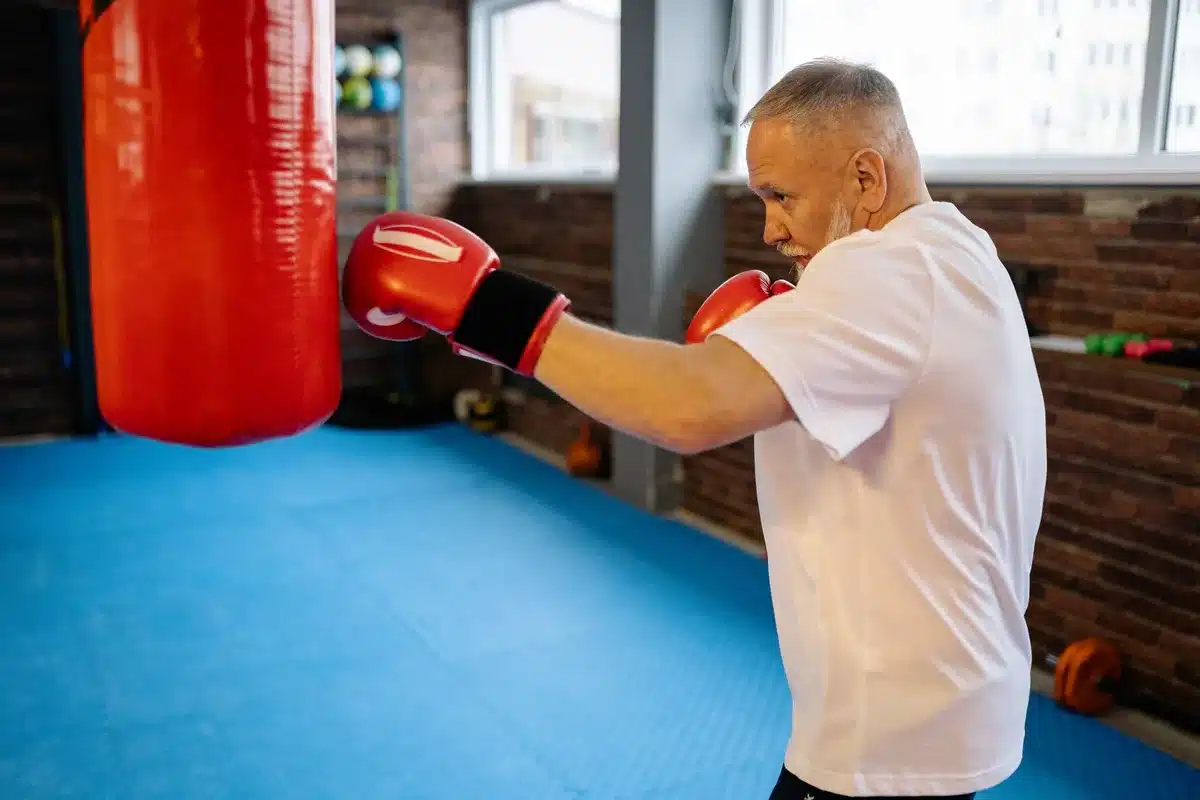 Personne âgée pratiquant un entraînement HIIT intense en salle de sport, en mouvement dynamique.