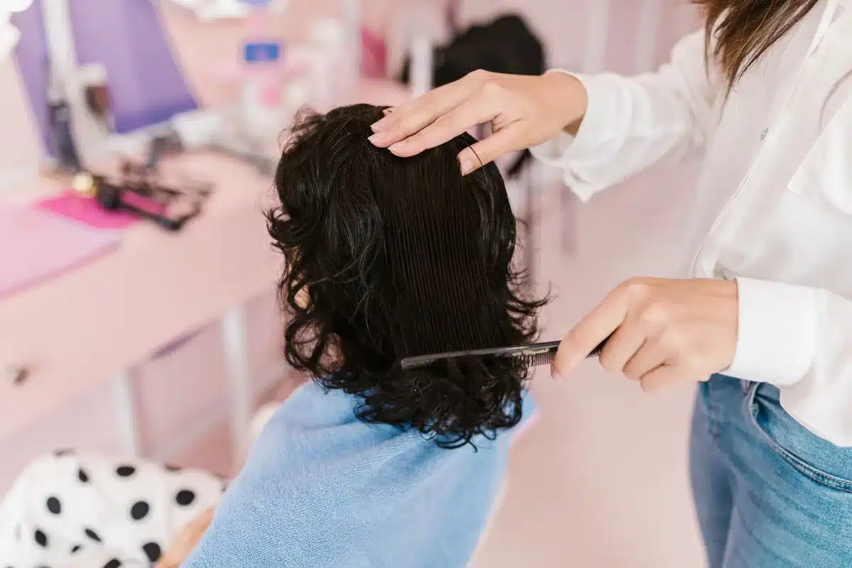 Mains appliquant un peigne fin dans les cheveux d'un enfant pour traiter les poux naturellement