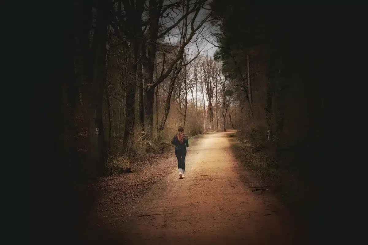 Un coureur en action sur un sentier, au lever du soleil, montrant l'effort et la régularité nécessaires pour perdre du p