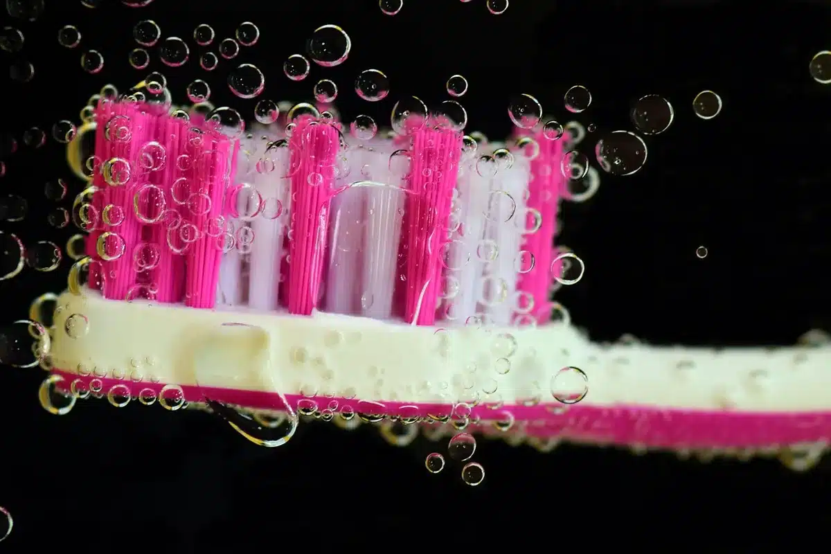 Personne nettoyant une façade avec une brosse douce et une échelle en plein jour