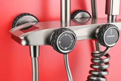 Mains ajustant un spot encastré au-dessus d'une cabine de douche carrelée