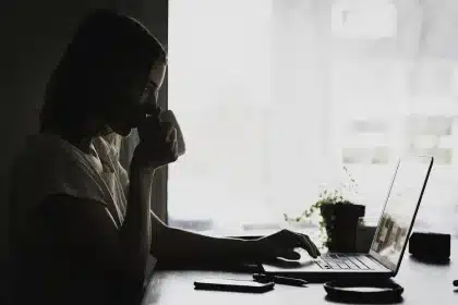 Femme à son bureau avec des papiers éparpillés, des tâches inachevées et des outils d'organisation désordonnés