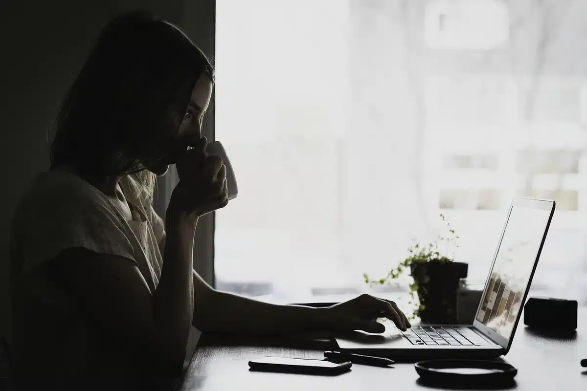 Femme à son bureau avec des papiers éparpillés, des tâches inachevées et des outils d'organisation désordonnés