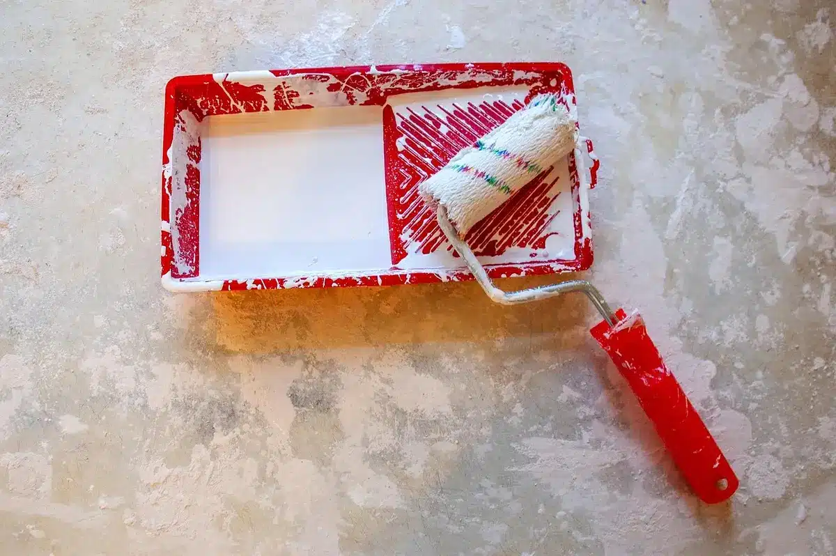 Bol, pinceau, gants et pinces disposés sur une surface claire