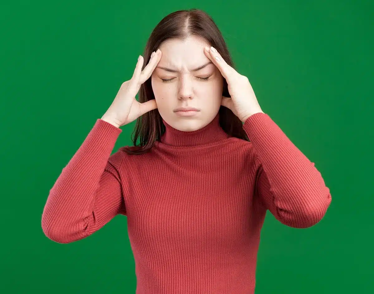 Femme souffrant de maux de tête et de douleurs, illustrant les manifestations physiques du stress émotionnel