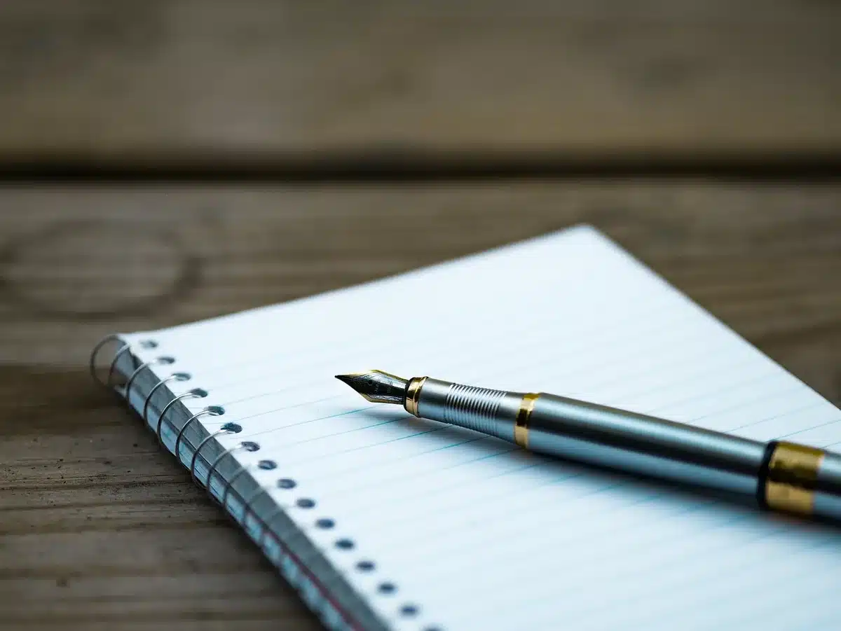 Carnet ouvert avec une liste de réussites et un stylo posé dessus