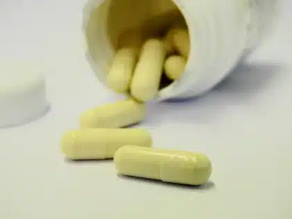 Boîte de compléments et flacon de gélules posés sur une table de gym, lumière du jour